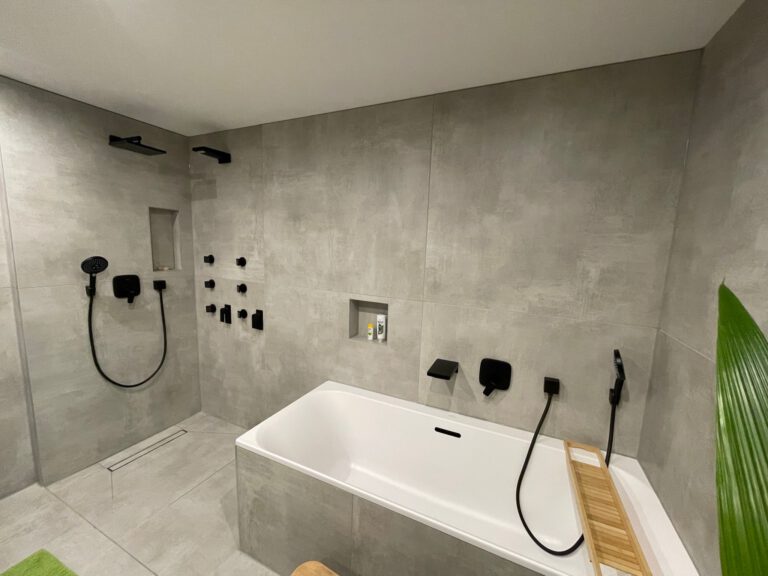 Badezimmer mit Badewanne und schwarzen Armaturen